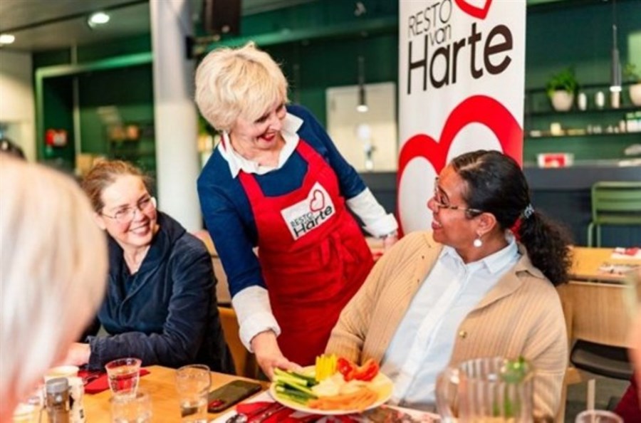 Mevrouw serveert maaltijd in Resto van Harte